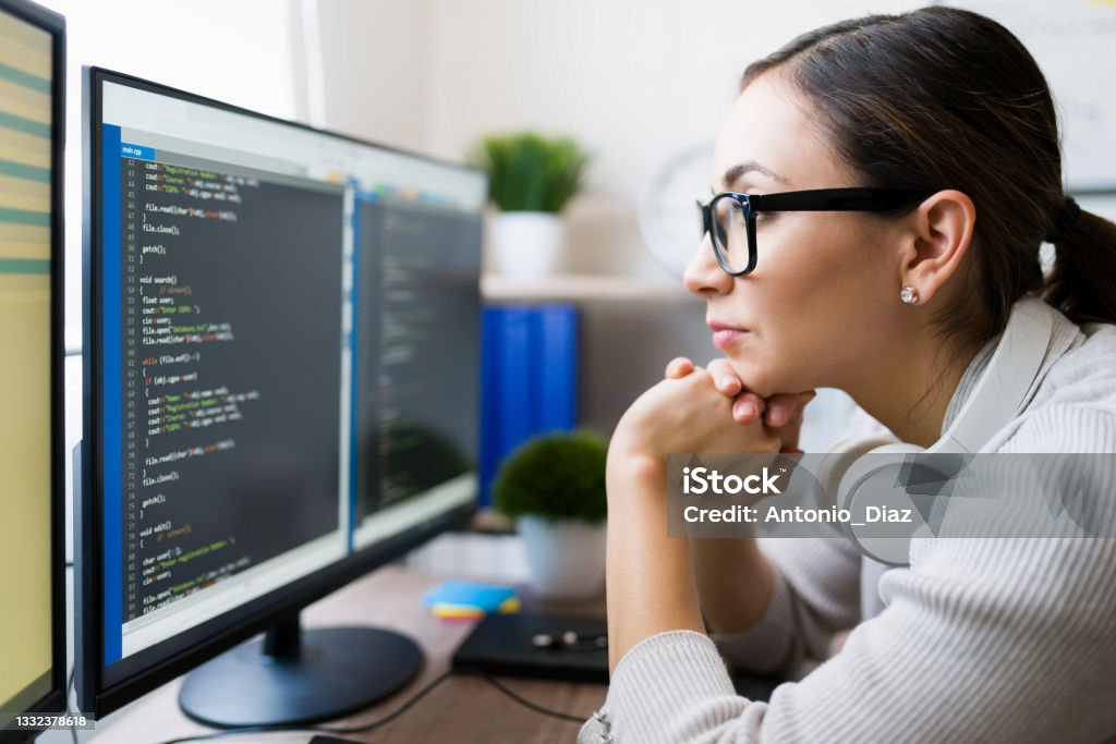 Close up of a smart young woman coding Profile of a hispanic freelancer wearing glasses and reading the coding software on the computer. Focused programmer checking the app code Computer Programmer Stock Photo