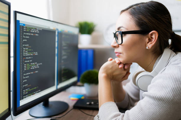 Close up of a smart young woman coding Profile of a hispanic freelancer wearing glasses and reading the coding software on the computer. Focused programmer checking the app code coding stock pictures, royalty-free photos & images