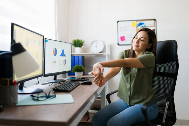 Beautiful woman doing stretching exercises at work Suffering from carpal tunnel. Attractive young woman stretching her arms and wrists after finishing working on her home desk as a business manager carpal tunnel syndrome photos stock pictures, royalty-free photos & images