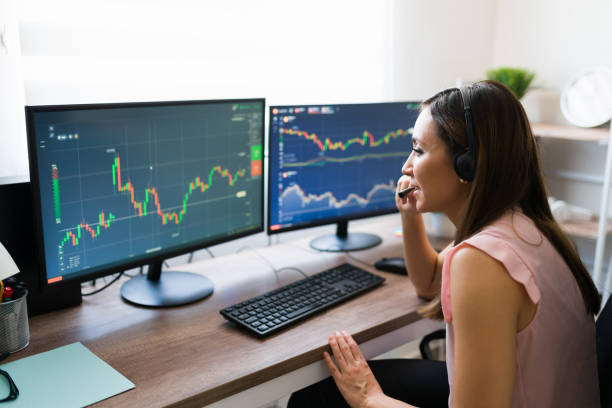 Talking with a customer about investing Do you want to do a business investment? Business analyst making a phone call to a client with a headset and checking the stock market stock trader stock pictures, royalty-free photos & images