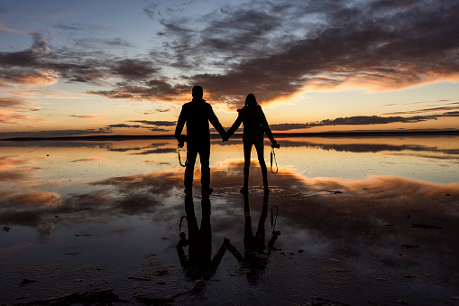 Photo of mother and 10 years old son standing by lakeshore and watching sunset. Shot under daylight with a full frame mirrorless camera.