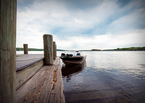 A sport fishing boat is tied up to a pier on Pewaukee Lake in Waukesha County, Wisconsin, on a gray summer morning.