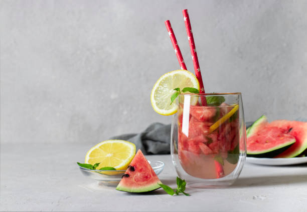 istock Cold Bright Watermelon Mojito cocktail with mint, lemon slices and drinking straw on light background with place for text 1332385957