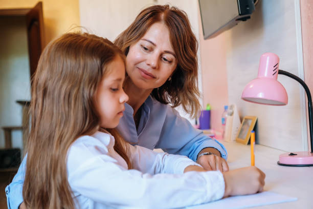 istock Mom helps her little daughter do homework 1332387069