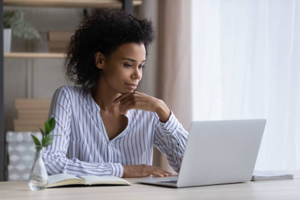 istock Pensive ethnic woman sit at desk work on laptop 1332387183
