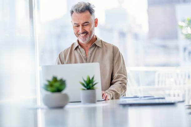 istock Mature businessman working at a desk on a laptop computer. 1332389667