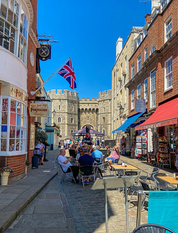 Windsor, United Kingdom - June 13 2021: Cafes and shops in a street next to Windsor Castle.