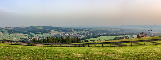 Nice green pasture with many wildflowers on a hill with a wide view of the Black Forest mountains, overlooking the summer landscape. Germany.