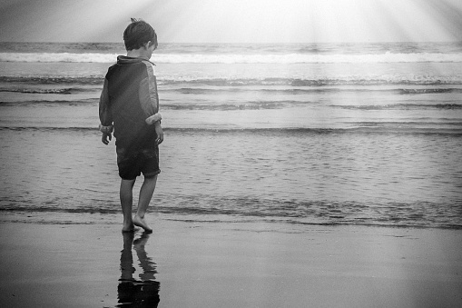Little boy walking in the beach from behind