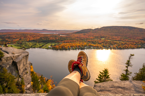 POV photo of a woman looking at Lyster lake with forest of Quebec and Vermont seen from the Mount Pinacle in Coaticook during autumn.