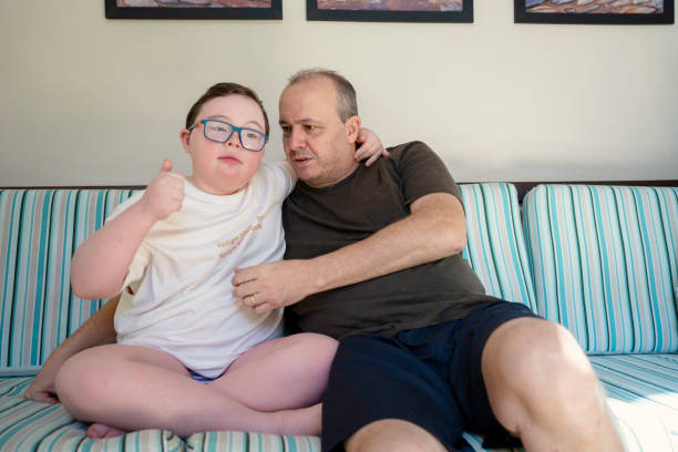 istock Father and son with down syndrome together in the sofa 1332392520