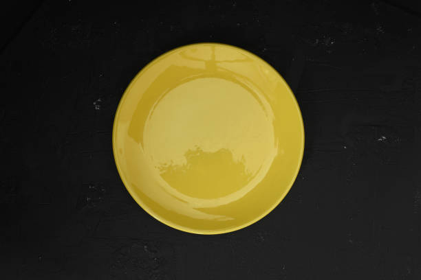 istock Empty yellow slate plate on dark stone table. Food background for menu, recipe. Table setting. Flatlay, top view. Mockup for restaurant dish 1332393609