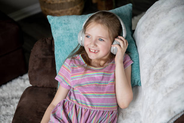 istock Elementary aged girl smiling while listening to her headphones 1332401933