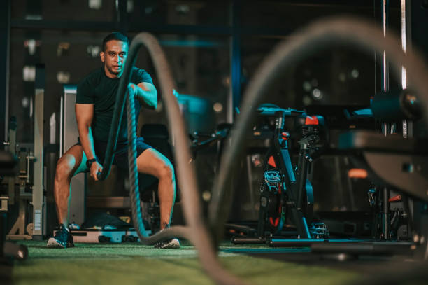 asiático indio medio adulto macho hombre practicando cuerda de batalla en el gimnasio - macho fotografías e imágenes de stock