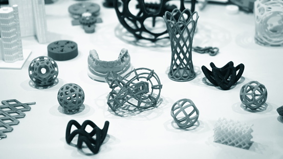 Many abstract models objects printed on a 3d printer on a white table. Fused deposition modeling, FDM. Progressive modern additive technology. Concept of 4.0 industrial revolution