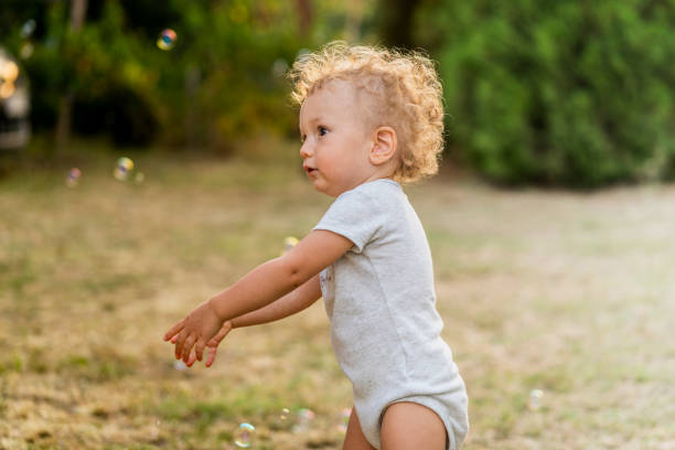istock Cute little toddler boy in bodysuits barefoot on grass 1332408912