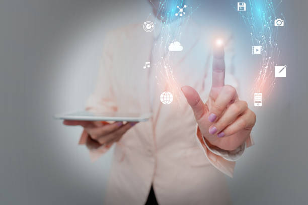 istock Business Woman Standing And Using Phone While Presenting New Futuristic Virtual Display. Lady In Suit Holding A Mobile Gadget Displaying A Holographic Interface Tech. 1332410790