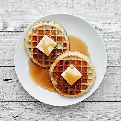 Viennese waffles with red caviar lie in a stack on a white plate, copy space