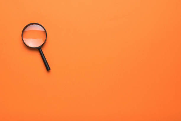 istock A small magnifying glass on an orange background. Space for the text. Flat lay. 1332417192