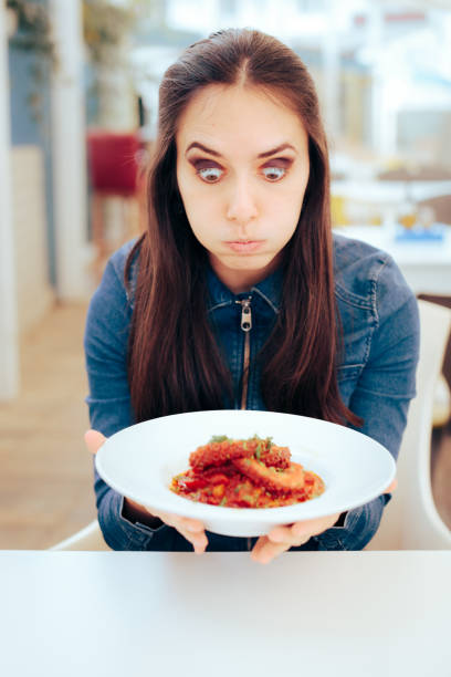 istock Funny Woman Looking at a Plate with an Octopus Dish 1332423172