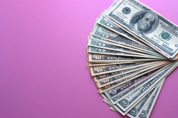 istock US dollars laid out on a pink background 1332426574