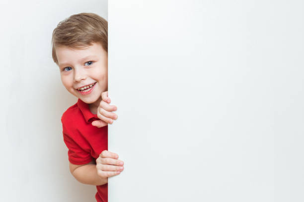 A little boy peeks out of torn paper.