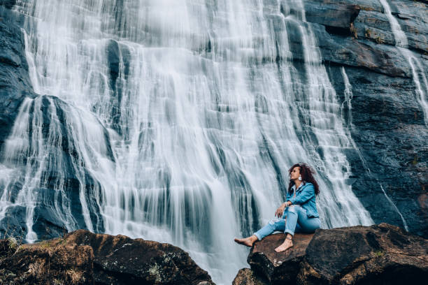 Woman resting on a rock in front of a waterfall