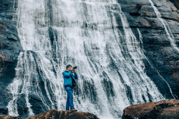 istock Nature photographer in front of a waterfall 1332431075