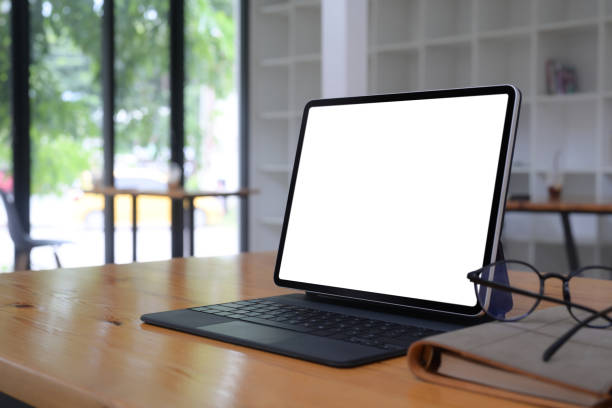 istock Computer tablet with lank display, glasses and book on wooden table. 1332431410