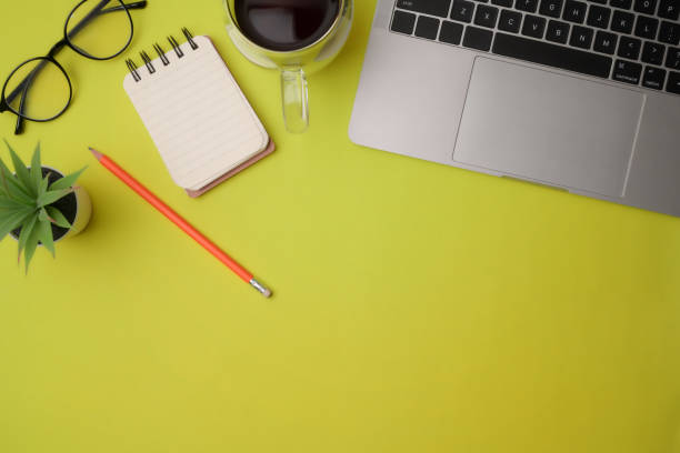 istock Computer laptop, notebooks, coffee cup and glasses on yellow background. 1332431446