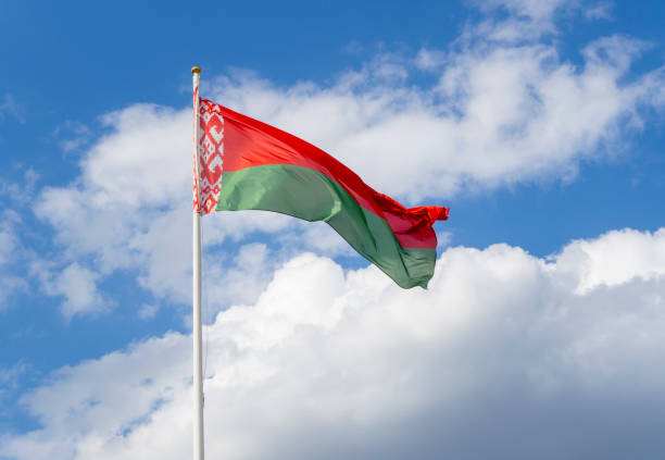 istock Flag of Belarus on flagpole waving against blue sky 1332436828