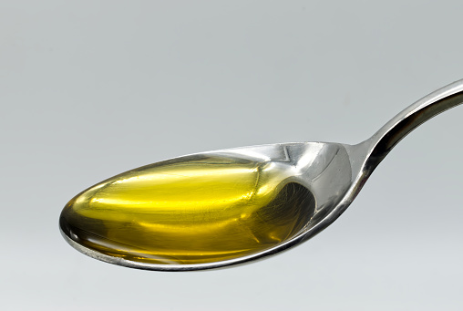 Extra virgin olive oil in a silver spoon isolated on white background