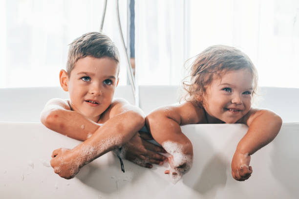 istock Two kids having fun and washing themselves in the bath at home. Posing for a camera 1332440803