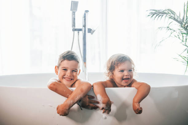 istock Two kids having fun and washing themselves in the bath at home. Posing for a camera 1332440817