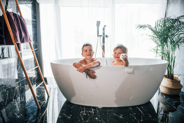 istock Two kids having fun and washing themselves in the bath at home. Posing for a camera 1332440832
