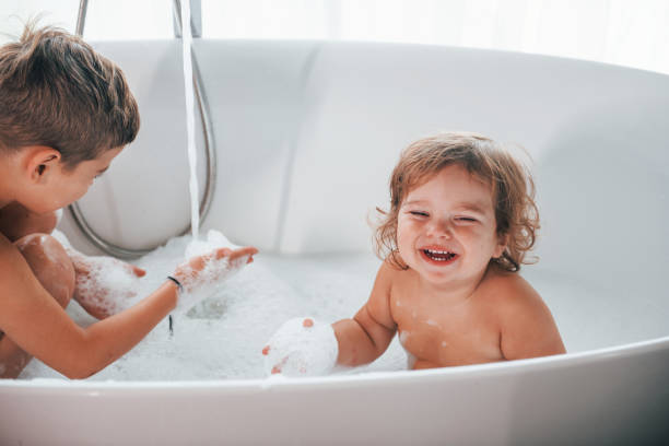 istock Two kids having fun and washing themselves in the bath at home. Posing for a camera 1332440892