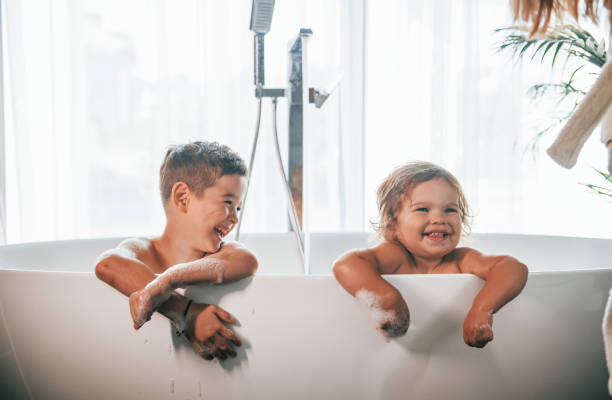 istock Two kids having fun and washing themselves in the bath at home. Posing for a camera 1332440948