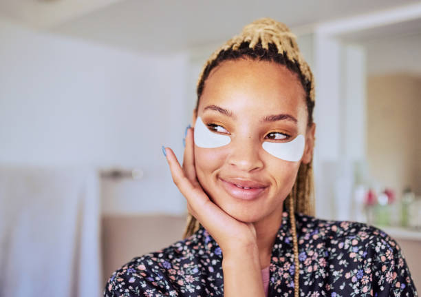 Shot of a woman wearing under-eye gel patches as part of her beauty regime It takes a minute to look your best one eyed stock pictures, royalty-free photos & images