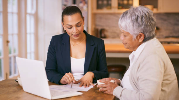 foto de un consultor pasando por el papeleo durante una reunión con una mujer de la tercera edad en casa - portfolio investment will tax fotografías e imágenes de stock