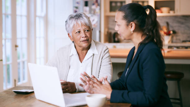 tiro de uma mulher sênior usando um laptop durante uma reunião com um consultor em casa - senior adult retirement financial advisor finance - fotografias e filmes do acervo