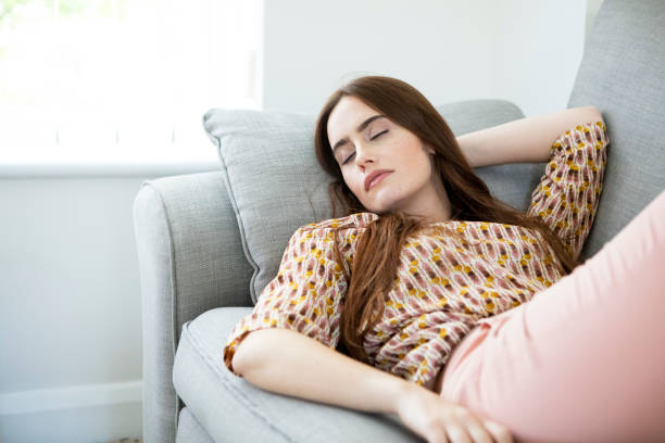 istock One young woman relaxing on a sofa, lying on her back with her eyes closed 1332443171