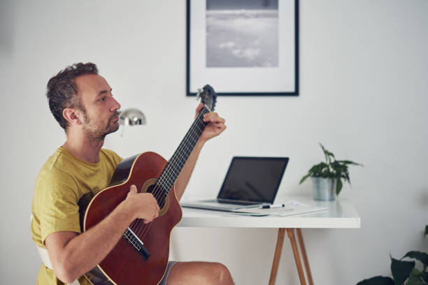 istock Man playing acoustic guitar at home. 1332450012