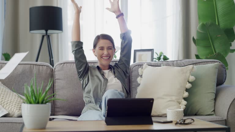 4k video footage of a young woman excitedly tossing paperwork into the air and cheering at home