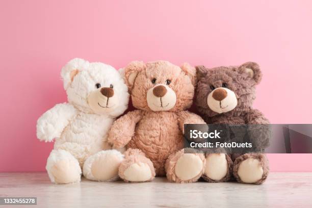 Smiling White Light Brown And Dark Brown Teddy Bears Sitting On Table At Pink Wall Background Pastel Color Togetherness And Friendship Concept Front View Closeup Stock Photo - Download Image Now