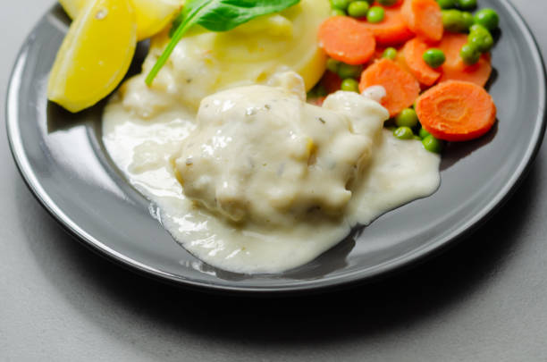 Cod Mornay, flaky cod with a creamy cheese sauce, with mashed potato, peas and carrots, British classic meal