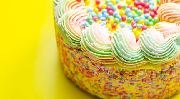 istock Madeira sponge coated with yellow colour frosting, layered with plum and raspberry jam, filled and topped with multicolour chocolate nibs and decorated with multicolour frostings and sugar decorations 1332462183