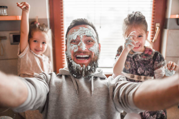 istock Selfie Time For Father Getting Face Stuck With Cream While Making Dessert With Female Children 1332464792