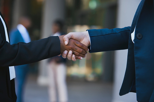 Business people in office suits standing and shaking hands, close-up. Business communication concept. Handshake and marketing.