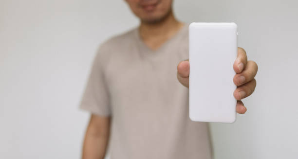Close up man holding white power bank. man wearing brown shirt holding energy reserves. Close up man holding white power bank. man wearing brown shirt holding energy reserves. battery hen stock pictures, royalty-free photos & images