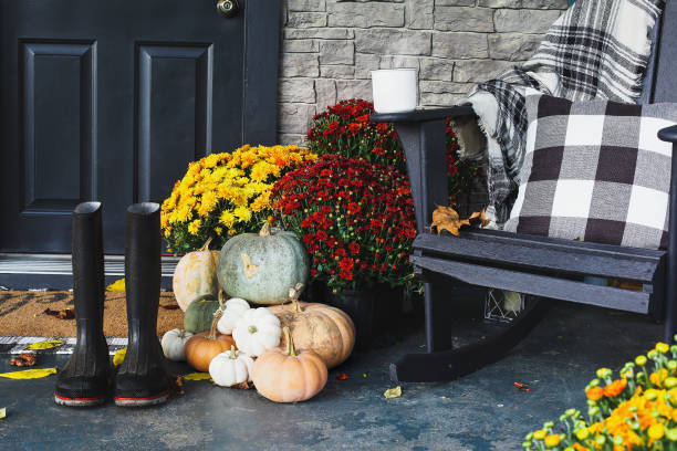 Hot Steaming Coffee Sitting on Chair on Front Porch Decorated for Autumn Hot steaming coffee sitting on rocking chair on front porch that has been decorated for autumn with heirloom white, orange, grey pumpkins, rain boots and mums. Selective focus with blurred foreground and background. chrysanthemum photos stock pictures, royalty-free photos & images